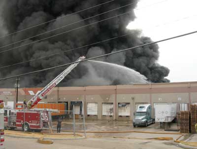 (3) In this photo, taken as the third-alarm companies were arriving, T-26 is operating its aerial stream in the vicinity of Door #20.