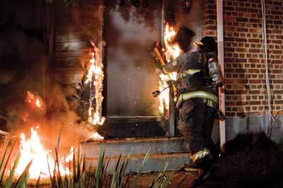 (5) It's realistic that one firefighter is conducting forcible entry operations alone; notice this firefighter is using a heavy striking tool as a substitute for not having a second firefighter to assist with conventional forcible entry. (Photo by Dave Hernandez.)