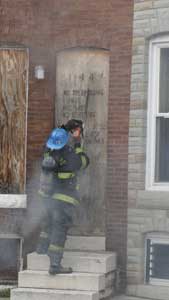 (6) Expect to encounter additional security devices on first-floor doors and windows; at this fire, the chain saw is required to first remove the outer plywood covering the doorway before the inward opening door can be forced. (Photo by Nick Eid.)