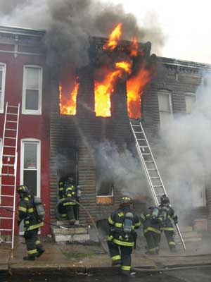 (8) Firefighters reposition portable ladders to the upper floors of the main fire building immediately after the fire has been knocked down on the first floor. (Photo by Christopher Hutson.)