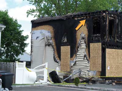 (9) The fire quickly and intensely progressed out the window and headed directly up to the eaves/soffits and entered the attic (arrow). (Photo by author.)