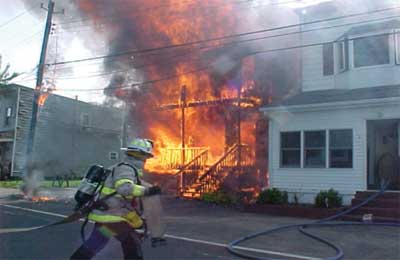 (10) At another fire, the home on the right, clad with aluminum siding, did not sustain even minor damage despite the severe exposure to radiant and convected heat. The exposure on the left is 75 to 100 feet away, and the vinyl siding is already melting, exposing the flammable wood and insulation underneath. (Photo by Tom Bierds.) 