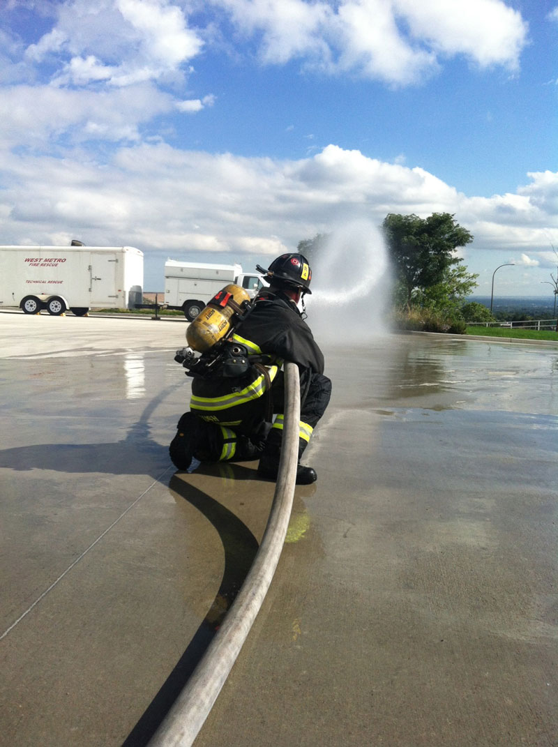 A firefighter training with a hosestream.