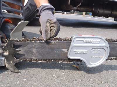 firefighter checks chain tension by pulling the chain out of the track and ensuring that it snaps right back in.