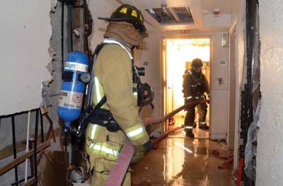 Two mules pull the hose laid out on the floor below the fire and push it up the stairs