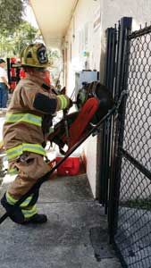 (1) The firefighter places a knee on the hook, keeping the chain taut, as he cuts through it. (Photos by Erika Stefani.)