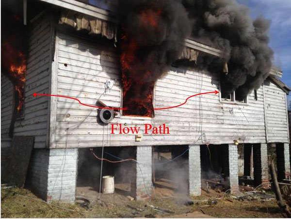 Fire vents from the rear windows of a home.