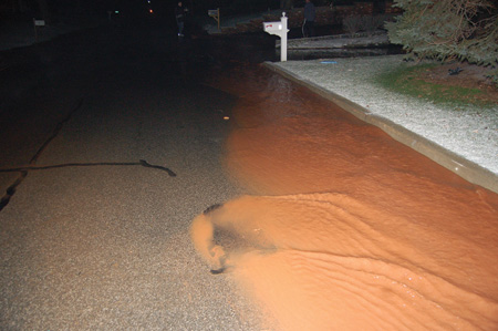 (1) Water flowing from a burst water main flows not only on the surface but also below it, undermining the street. Is this water only a few inches deep or does it conceal a deep sinkhole? (Photo 1 by Thomas Bierds; other photos by author unless noted.)