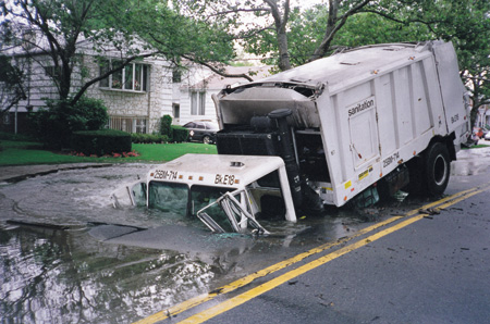 The truck's driver drove into what he thought was a puddle, but it was actually a sinkhole created by a burst underground water main. The undermined roadway collapsed under the truck's weight.