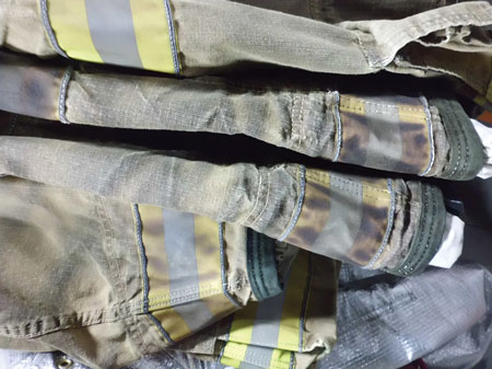 (1) Firefighter clothing becomes discolored or soiled with a variety of fireground substances, including soot, debris, and a variety of liquids. These soils potentially contain a large variety of persistent contaminants that remain in the clothing. <i>(Photos courtesy of Gear Cleaning Solutions.)</i>