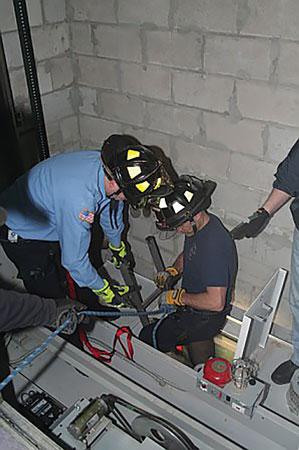 (1) The firefighters are wearing proper PPE while working in the elevator shaft. A top escape hatch removal, as shown in this photo, is the last resort for removing the passenger. A fall arrest system must be implemented for firefighter and passenger safety. (Photos by author.)