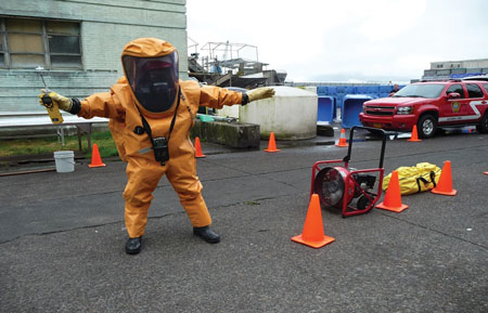 (4) A hazardous materials entry team member undergoes initial gross decontamination from a smoke ejector fan after simulated exposure to anhydrous ammonia vapors in the hot zone. This was followed by a complete wet technical decontamination process.