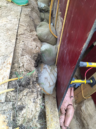 (2) Sandbags are placed behind the panel as backfill; they can contain soil to prevent it from running under trench panels. 