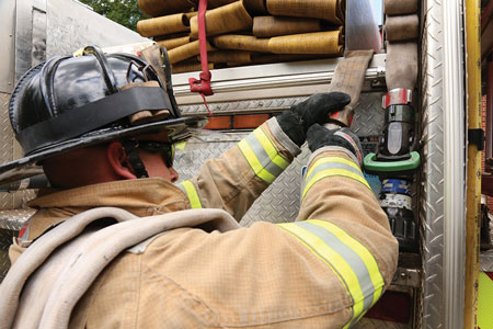 <b>(13) </b>The nozzle firefighter shoulders the 150-foot 1¾-inch preconnected minuteman load and advances it forward enough so the driver/engineer can shoulder the remaining 100 feet of flat-loaded hose and disconnect the line from the jumper (pony) line. <i>(Photo 12 by Michael Clark; photo 13 by Matt Van Ness.</i>)