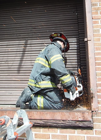 (3) Using a rotary saw, this officer is making a box cut on a fortified steel roll-up door.