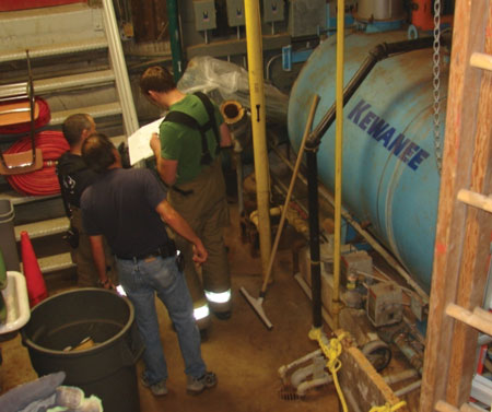 (2) Firefighters look over the layout and hazards in the basement of an apartment building after they rendered care at an emergency medical services call.