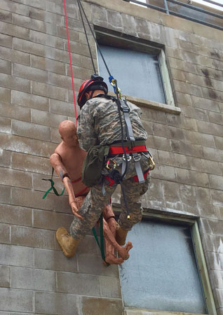 (11) This Michigan National Guard soldier is practicing a pickoff of a worker who had fallen onto his lifeline. The rescue team is using a top-down rope rescue system.