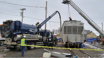 (1) Personnel prepare the tube kit to attach to the vacuum truck for material offloading. (Photo by Jamie Renner.)