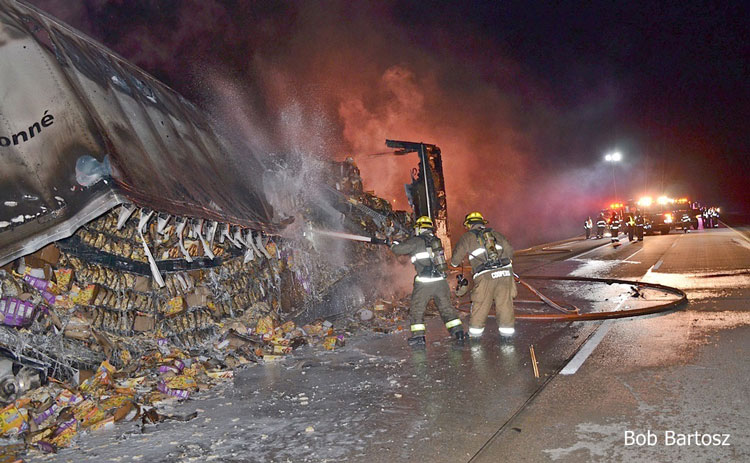 Firefighters apply water to a burning semi truck