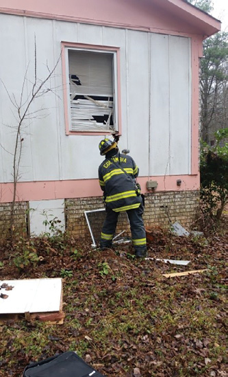 (2) This firefighter is using a hand tool to convert a window in this wood-frame house. 