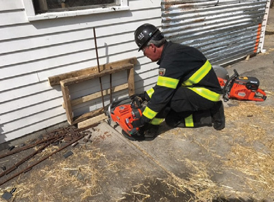 (1) When faced with low cutting operations, a firefighter can use his foot to help support the saw, which also takes some of the vibration off his arms while cutting. (Photos by Josh Materi.)