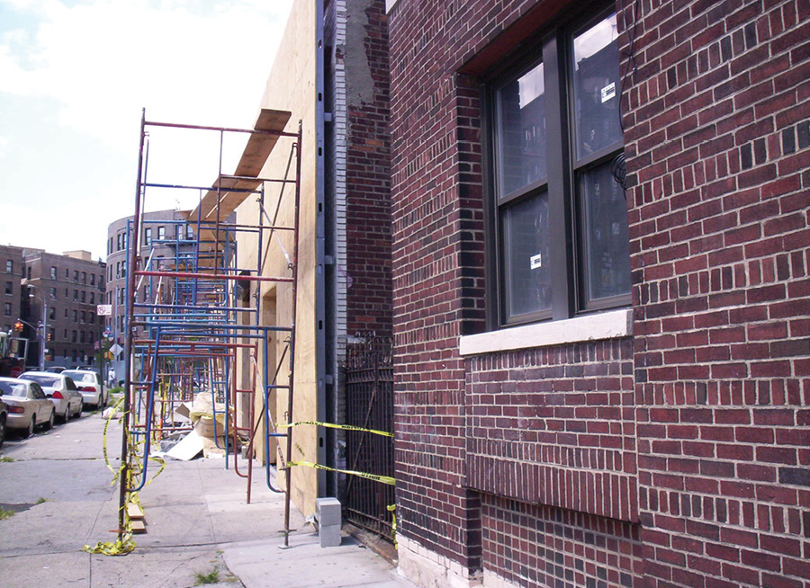 The studs run from the ground to the top of the parapet, creating a void between sections. Fire could travel inside this void along the back side of the plywood. 