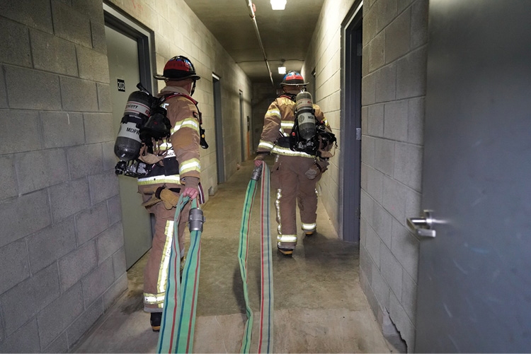 Firefighters pull the couplings down the hallway.   