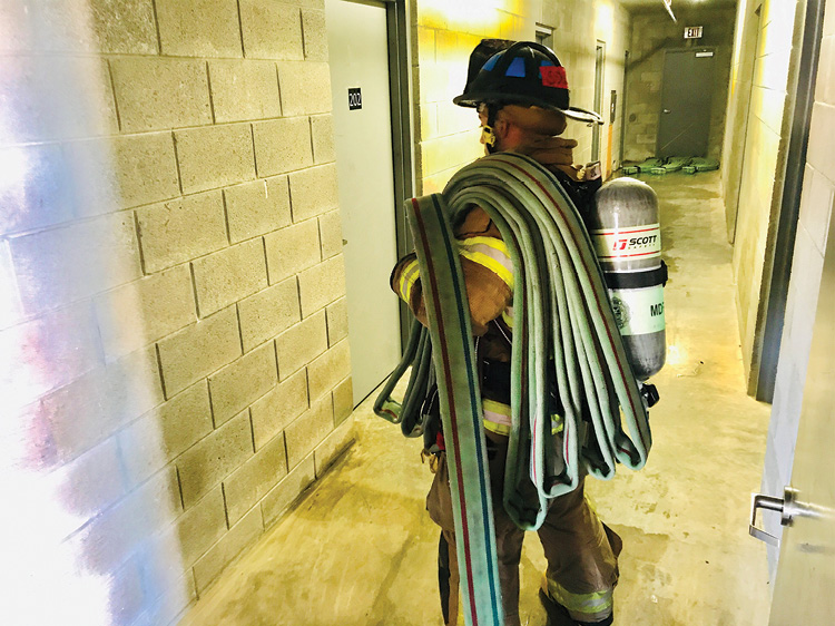 (19) Stretching the bundle from the functioning standpipe to the attack stairwell without a functioning standpipe. Note the hose bundles in the hallway outside the attack stairwell door. (Photo by Shawn Thompson.) 