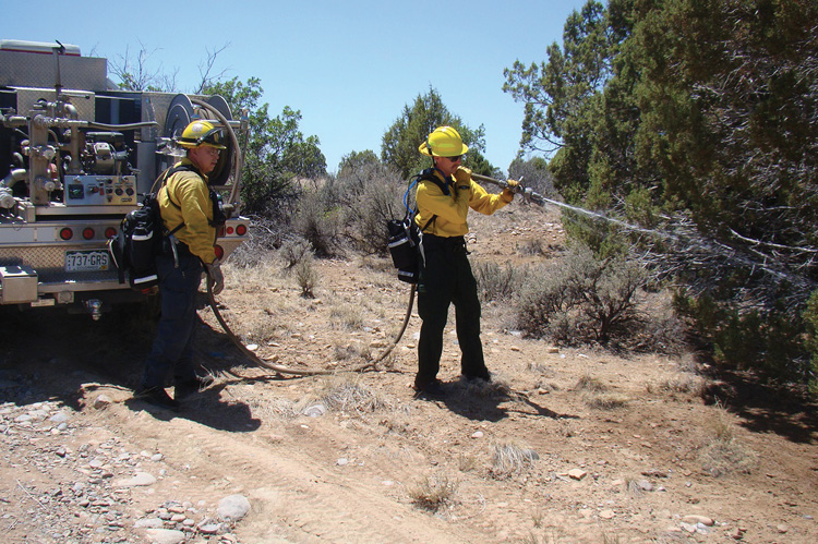 Firefighters create a wet line using the hose reel mounted on the brush truck.