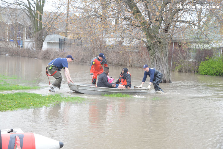 Firefighters help residents onto a boat to remove them from flooded areas