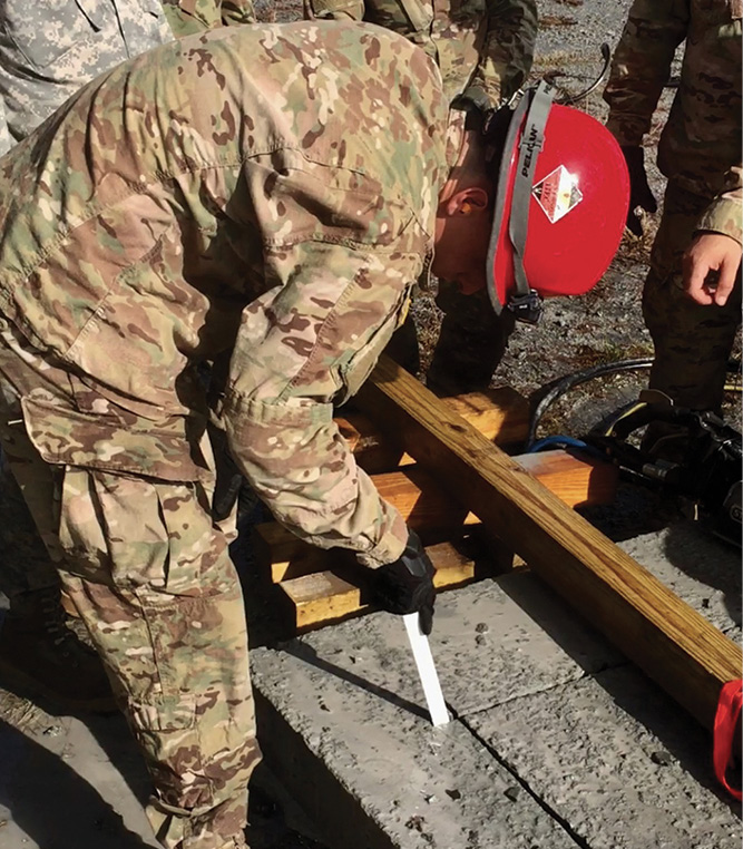 The soldier uses a reciprocating saw blade to see where the concrete has not been completely cut. 