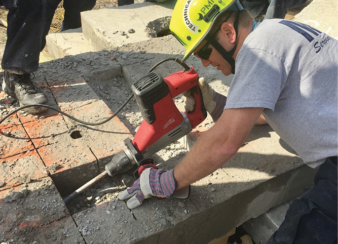 MFD firefighters chip concrete to create a channel. This lower level will allow the saw to fully penetrate the concrete on the next pass. 