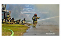 Firefighters direct a stream at the building from the ground.