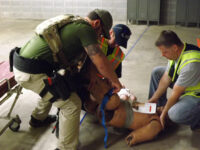 Responders assess and mitigate injuries to a patient before transport.