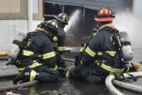 Two firefighters operating lines at the scene of the warehouse fire