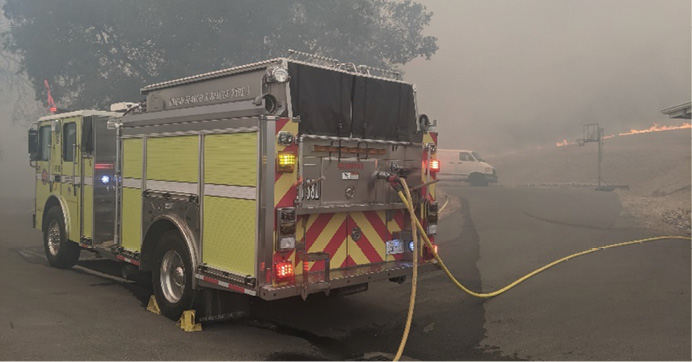 A Type I engine prepares to protect multiple structures as the fire front approaches.