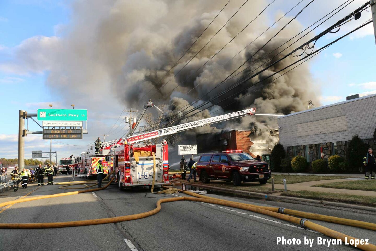 Aerial device in use over large commercial building on Long Island with smoke condition