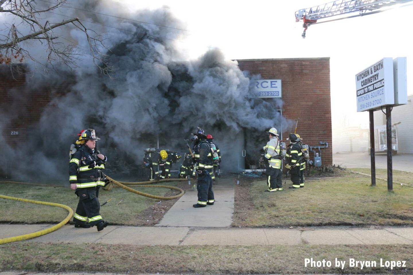 Firefighters with hoselines and smoke condition emanating from building