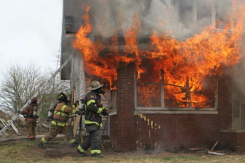 Firefighters confront a large volume of fire in a home