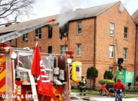 Firefighters remove a woman from an apartment fire via ground ladder