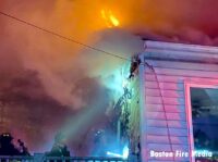 Boston firefighters and flames at a dwelling fire