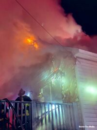 Flames shoot from the roof as Boston firemen work