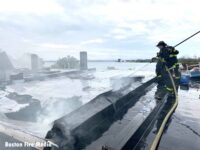 A firefighter with a hose on a roof