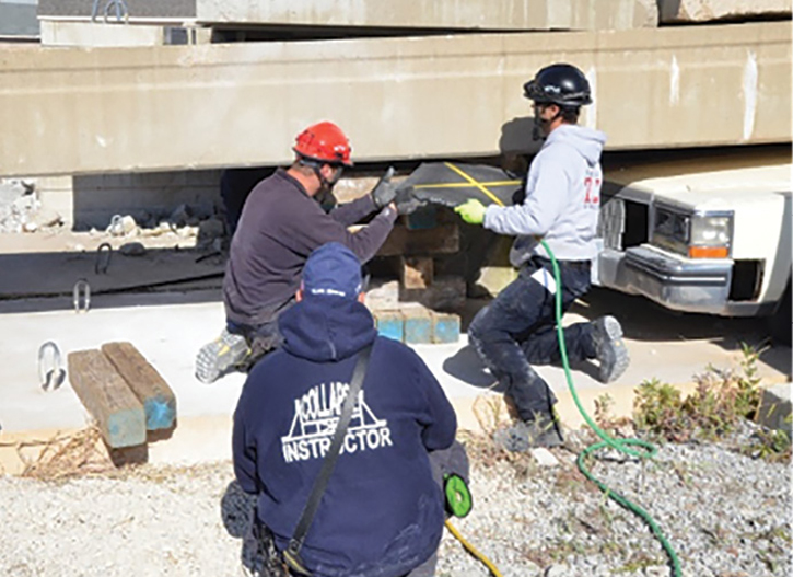 Students in the 56-hour Illinois Fire Service Institute Structural Collapse Rescue Technician course performing a bridge beam lift with a trapped vehicle underneath, the lift used to rescue the worker in this incident.