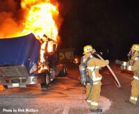 Two firefighters with a hoseline at a big rig fire