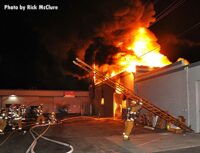 Flames rage outside a building as LAFD crew members work