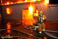 City of Los Angeles firefighter with flames shooting through a building in the background