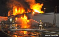 Firefighters train hoselines on a burning building in Los Angeles