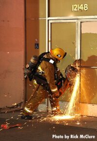 LAFD firefighter using a power saw to cut through a door