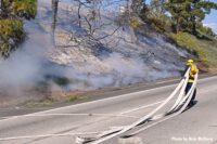 Firefighter stretches out hoseline at brush fire